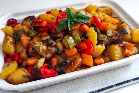 Un plat coloré de recette caponata sicilienne traditionnelle au four, avec des légumes rôtis et une touche de basilic frais.