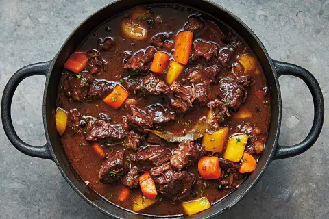 En mustig kalops i gjutjärnsgryta, perfekt för ett klassiskt kalops recept. Kött, morötter och potatis i en mörk sås.