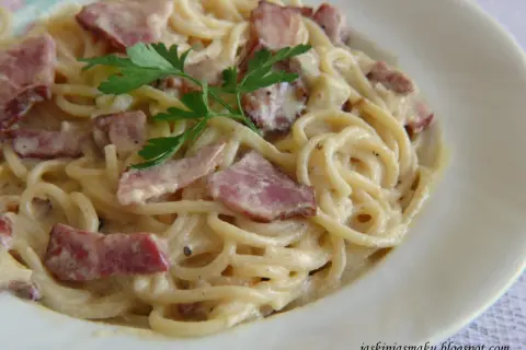 Pyszne spaghetti z boczkiem w kremowym sosie, udekorowane natką pietruszki. Idealne danie dla miłośników włoskiej kuchni.