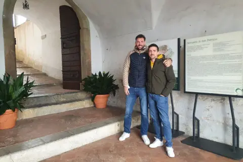 Due amici sorridono davanti al Santuario di San Patrizio, un luogo storico.