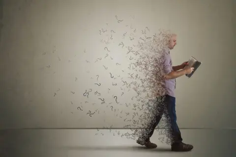Ein Mann liest ein Buch, während er sich in Fragezeichen auflöst. Ein Symbol dafür, wenn der Glaube nicht mehr passt und Zweifel aufkommen.