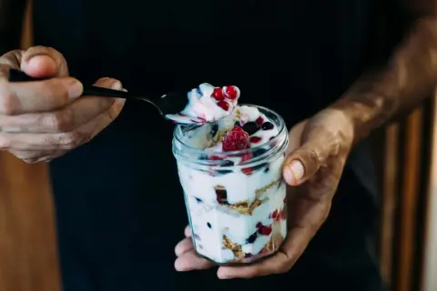 Ein Glas mit Magerquark, Beeren und Knuspermüsli. Perfekt für gesunde Magerquark Rezepte.