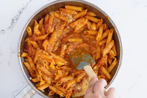 Macarrones con huevo y salsa de tomate en sartén, listos para servir.