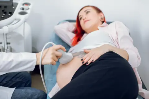 Badanie USG ciężarnej kobiety. Lekarz wykonuje badanie, by wykluczyć zespół Edwardsa.