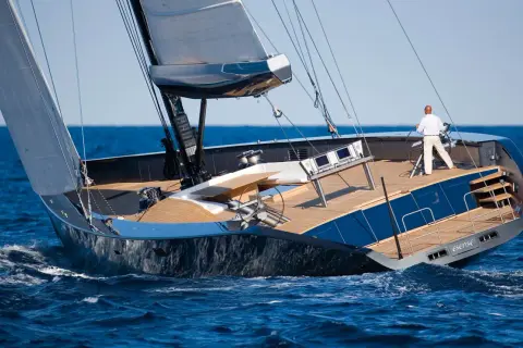 Il Wally Esense naviga con vele spiegate, un uomo al timone. Lusso e velocità sull'onda blu.