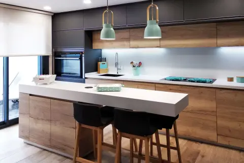 Cocina moderna con isla y taburetes. Ideas cocinas pequeñas: gabinetes de madera, encimera blanca y detalles en verde menta.