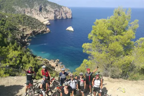 Grupo de ciclistas disfrutando de una ruta de ibiza en bicicleta con vistas espectaculares al mar Mediterráneo.