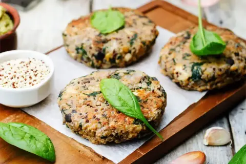 Pyszny obiad bez mięsa: burgery z komosy ryżowej i szpinaku, z dodatkiem czosnku i świeżych liści.
