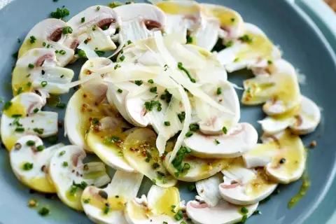 Frische Champignons, mariniert mit einer leichten Vinaigrette, gehobeltem Parmesan und Schnittlauch – eine tolle Idee für Vorspeisen.
