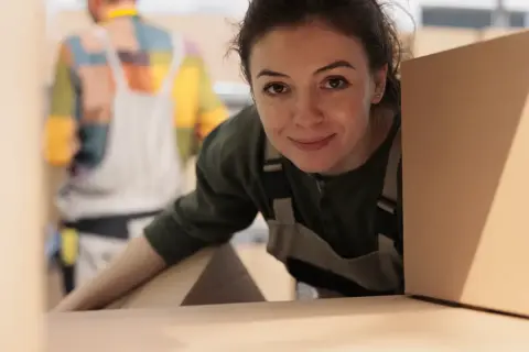 Donna sorridente con scatole, pronta per organizzare un trasloco senza stress.