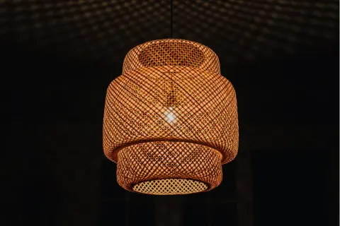 Pleciona, bambusowa lampa ruchoma rzuca na sufit cień przypominający siatkę.