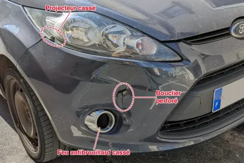 Avant le contrôle technique : feu antibrouillard avant cassé, bouclier perforé et projecteur endommagé sur une voiture grise.