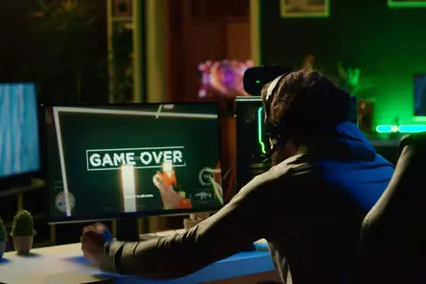 Gracz sfrustrowany przegraną, ekran "GAME OVER". Może to znak, że czas pomyśleć, jak zmniejszyć ping i poprawić swoje wyniki w grach online.