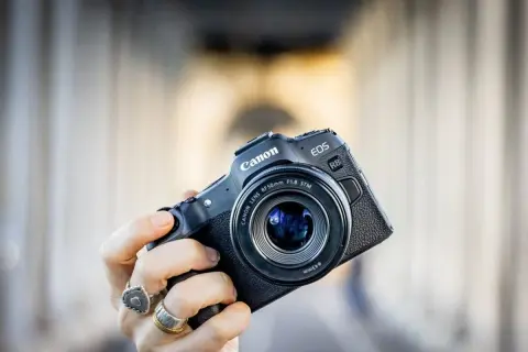 Mano che tiene una fotocamera Canon EOS R8 con obiettivo 50mm f/1.8 STM. Un modello compatto, ideale per chi cerca la qualità di un sensore canon apsc.