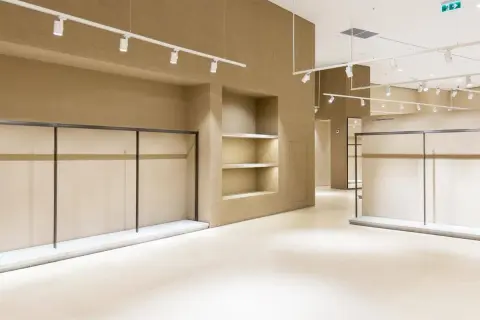 Interni di un locale commerciale in fase di ristrutturazione, con scaffalature vuote e illuminazione a faretti.