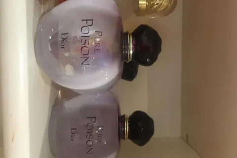 Dwa flakony perfum Pure Poison Dior 100ml, każdy z fioletową poświatą i czarnym korkiem.