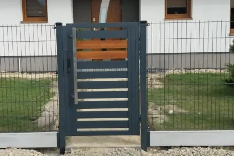 Nowoczesna furtka z metalu i drewna, osadzona na betonowym łączniku podmurówki.