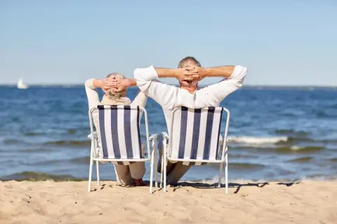 Para seniorów cieszy się wczasy nad morzem z dojazdem z Katowic, relaksując się na plaży.