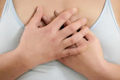 Hände umfassen die Brust, als ob sie brustbein schmerzen lindern wollen.