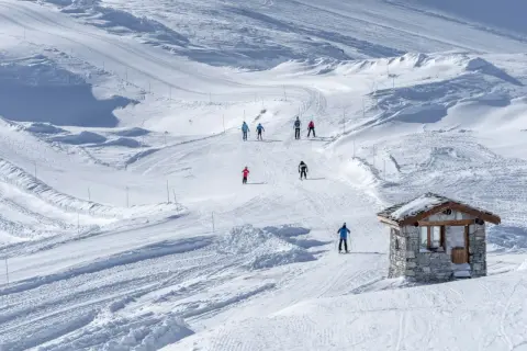 Sciare in un paesaggio innevato, perfetto per una settimana bianca in Piemonte. Piccola baita di pietra sulla pista.