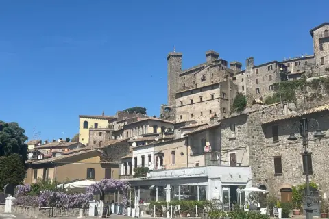 Borgo medievale sul lago di Bolsena, cosa vedere: un castello imponente, case in pietra e un ristorante fiorito.