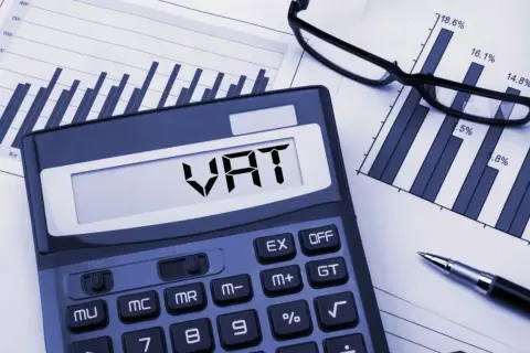 Kalkulator z napisem VAT, wykresy i okulary. Analiza zwolnienia podmiotowego z VAT.
