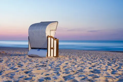 Pusta plaża o zachodzie słońca, idealna na tanie miejscowości nad morzem. Wygodny kosz plażowy czeka na turystów.