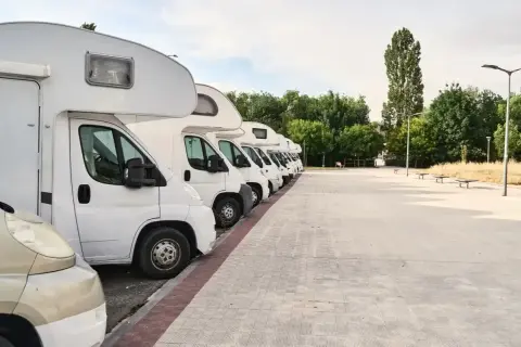Fila de autocaravanas blancas aparcadas en un área de descanso. Consulta el precio parking caravanas para tu próxima aventura.