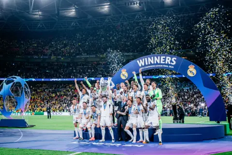 Piłkarze Realu Madryt świętują zwycięstwo w Lidze Mistrzów 2024, podnosząc trofeum wśród konfetti.