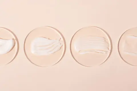 Vier Cremeproben auf Glasplättchen: eine reichhaltige, eine seidige, eine gestreifte und eine transparente. Ideal für Hautpflege mit niacinamide und vitamin c.