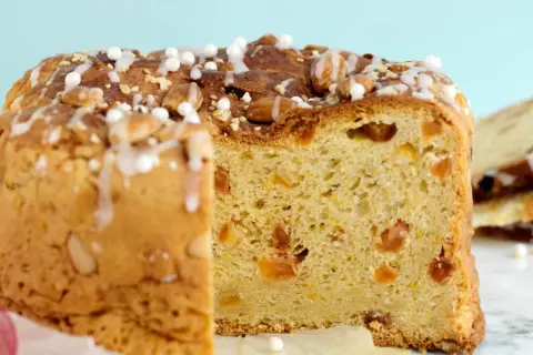 En skiva av ett gyllene panettone, dekorerad med mandlar och glasyr. Detta är ett recept på original panettone.
