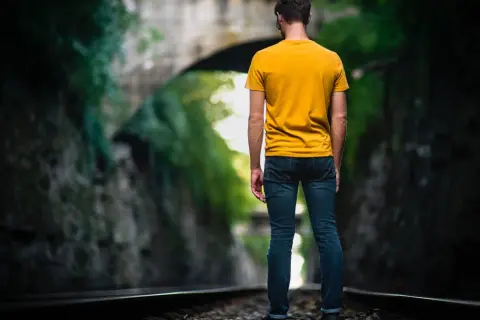 Man op spoor, omringd door groen. Een metafoor voor het navigeren door het leven met hsp, waar elke stap bewust gezet moet worden.