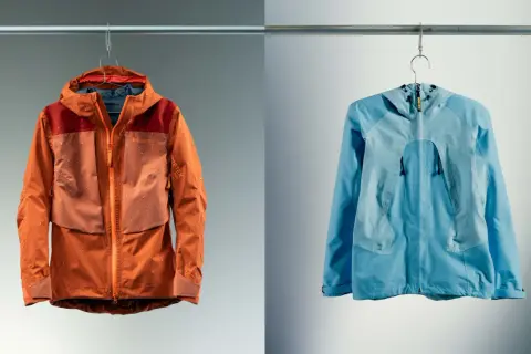 Deux vestes, une orange et une bleue, suspendues. La veste orange est mouillée, montrant l'efficacité du Gore-Tex.