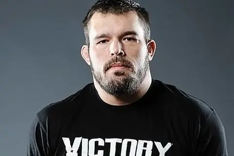 Dean Lister, en tuff MMA-fighter med skägg och en svart t-shirt med texten "Victory MMA & Fitness".