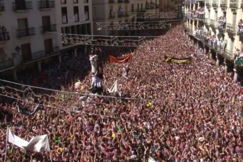 Multitudinaria plaza de Teruel, con gente en balcones y calles, celebrando el chupinazo.