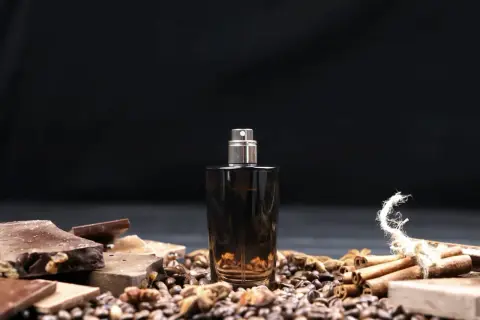 Męskie perfumy arabskie w ciemnej butelce, otoczone czekoladą, kawą i cynamonem.