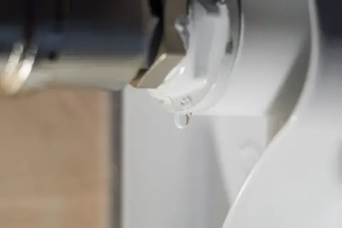 Gota de agua cayendo de un componente metálico, indicando la necesidad de desmontar radiador para reparación.