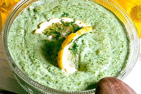 En skål med krämig salsa verde, garnerad med citronskivor och dill. Perfekt till sommarmaten!