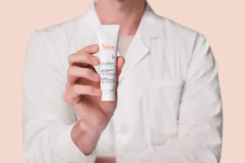Mano sosteniendo un tubo de crema Avène Cicalfate+, ideal para piel irritada.