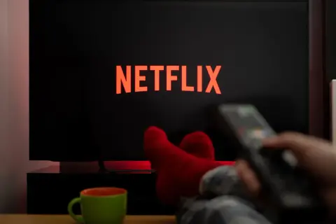 Relaks przy Netflixie. Jak włączyć gry? Czerwone skarpety, pilot w dłoni i kubek napoju.