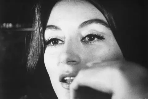 Nahaufnahme von Anouk Aimée, deren Blick nachdenklich ist. Sie erinnert an eine vergangene Liebe, vielleicht ihren Ehepartner.