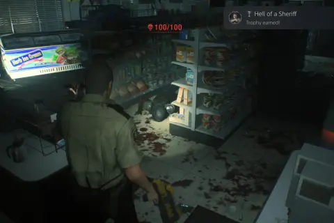 Policjant w sklepie, gdzie widać plamy krwi i półki z produktami. Osiągnięto trofea Resident Evil 2 "Hell of a Sheriff".