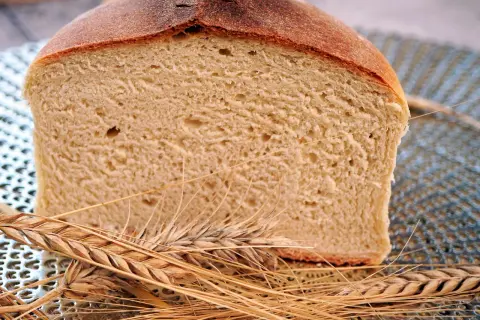 Kromka chleba z gęstym miąższem i spieczoną skórką, otoczona kłosami. Zastanawiasz się, dlaczego chleb nie wyrósł?