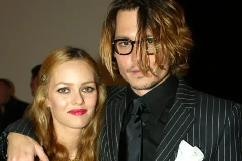 Johnny Depp i Vanessa Paradis na gali. Johnny w okularach i garniturze w paski, Vanessa z błyszczącymi ustami.