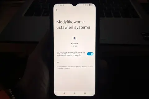 Ekran telefonu pokazuje ustawienia systemu, gdzie można sprawdzić, jak włączyć kamerę w telefonie.