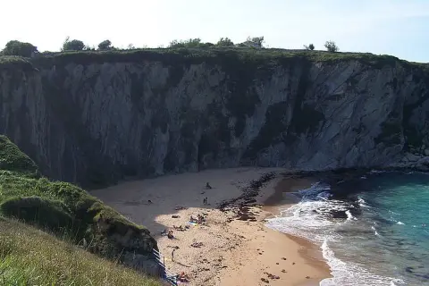 La **playa de la rabia**, un rincón escondido entre acantilados, recibe a unos pocos bañistas que disfrutan del sol y el mar.
