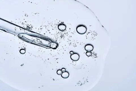 Kropla serum z pipetką, bąbelki unoszące się w żelu. Czy peptydy można łączyć z witaminą C? To pytanie nurtuje wiele osób dbających o cerę.