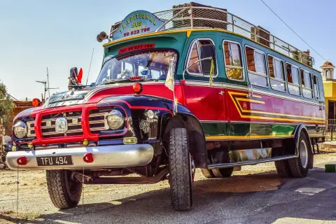 Tradycyjny autobus na Cyprze, kolorowy pojazd z napisem "Traditional Bus Cyprus" i numerem telefonu, stanowi unikatowy element komunikacji miejskiej.