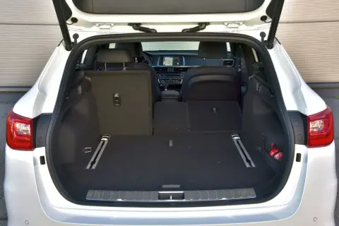 Otwarty bagażnik białej Kia Optima kombi. Wnętrze jest puste, gotowe na podróż.