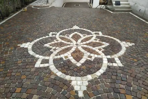 Vicolo carrabile in porfido con un elegante motivo floreale centrale.
